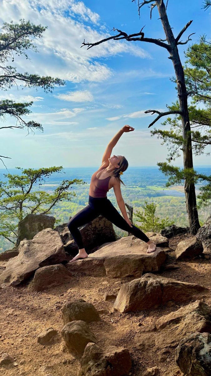 Priscila in a side-angle yoga pose on a mountain overlook
